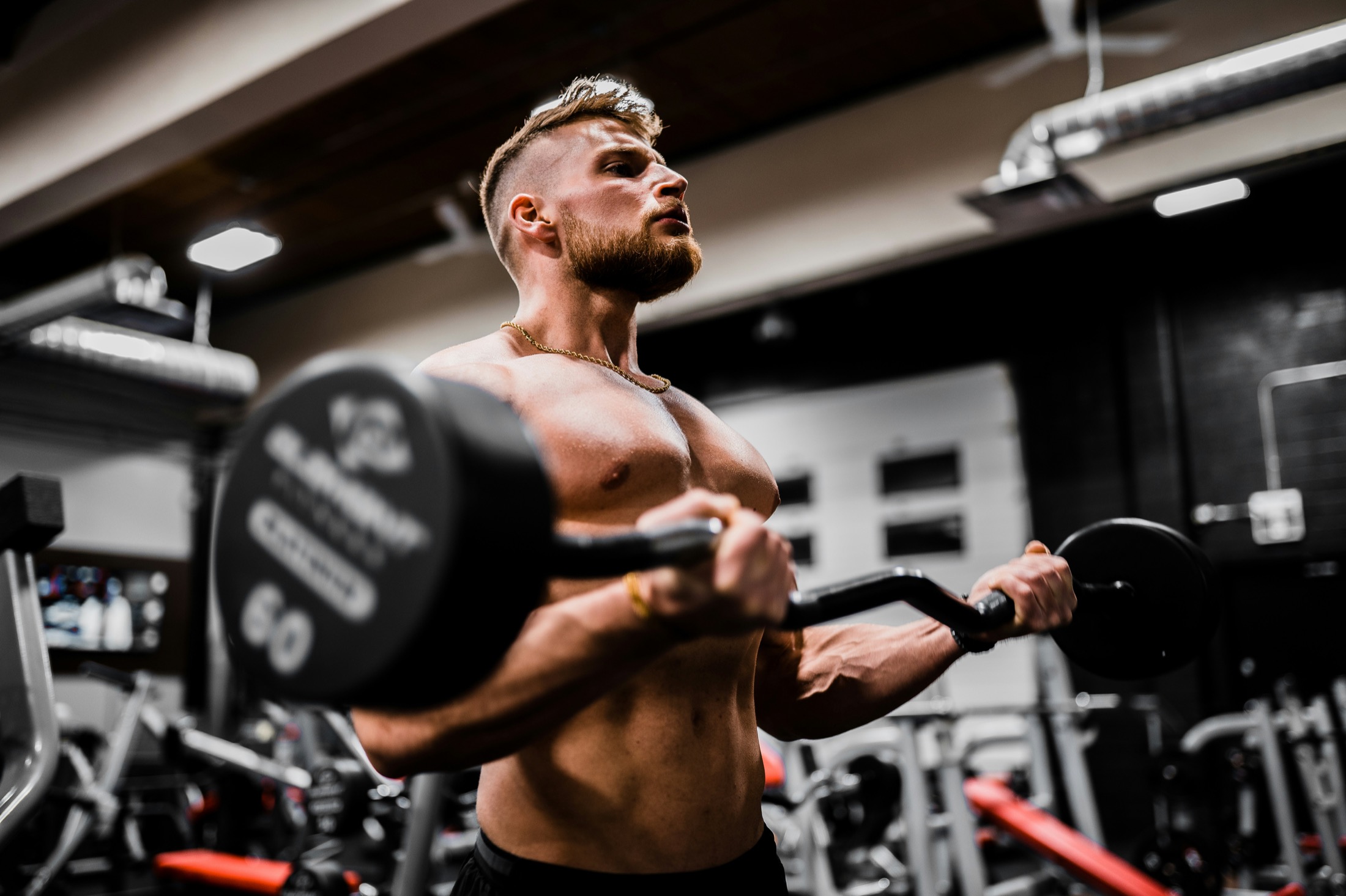 Athlete performing a barbell curl in a gym